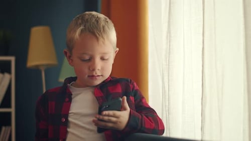 Boy Using Smartphone Indoors By Window