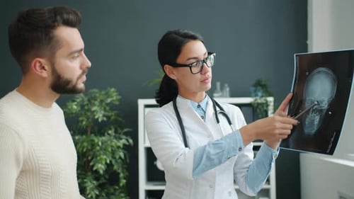 Patient and Doctor Looking at X-ray Images in Clinic Office Talking Discussing Disease