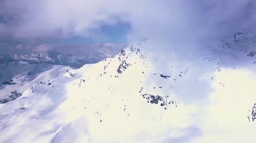 Drohnenaufnahme aus der Luft von strahlend weißem Schnee und wolkenbedeckten Bergen über dem Skigebiet