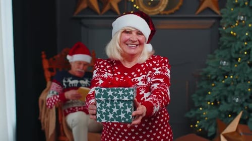 Mature Woman Offers Christmas Gift with Festive Smile