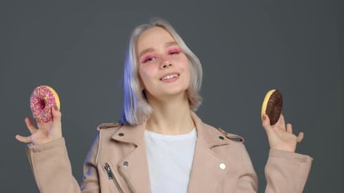 Blonde Woman Holds Up Two Donuts
