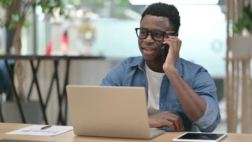 Adult Talking on Phone at Desk With Laptop