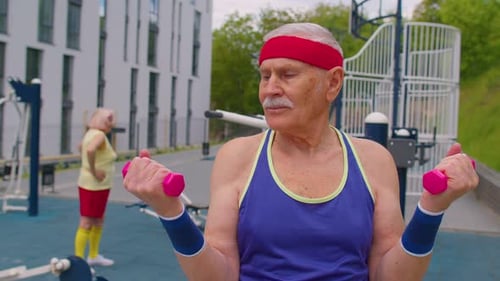 Elderly Senior Man Grandfather Doing Training Weightlifting Exercising with Dumbbells on Playground