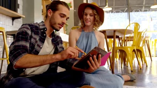 Young Adults Collaborating with Tablet in Modern Cafe