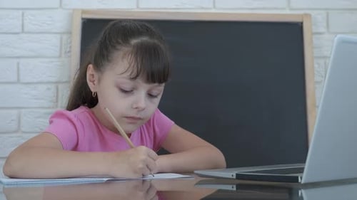 Girl Studying with Laptop Writing in Notebook