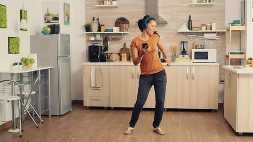 Woman Dancing and Singing in Kitchen with Headphones