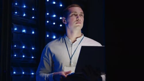 Concept of Digitalization of Information IT Specialist In Front of Server Racks with Laptop