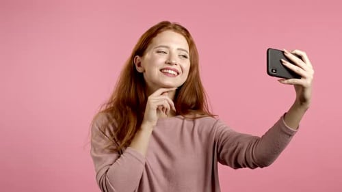Smiling Woman Taking Selfie with Smartphone on Pink