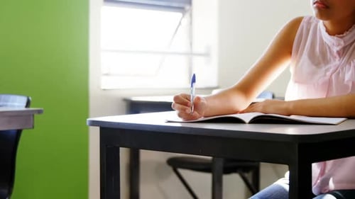 Focused Student Writing in Classroom at Desk