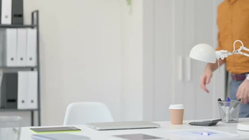Man Opens Laptop at Desk in Bright Office