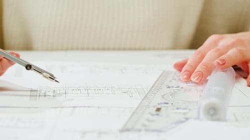 Architect Designer Using Compass to Draw Plan Blueprint Closeup