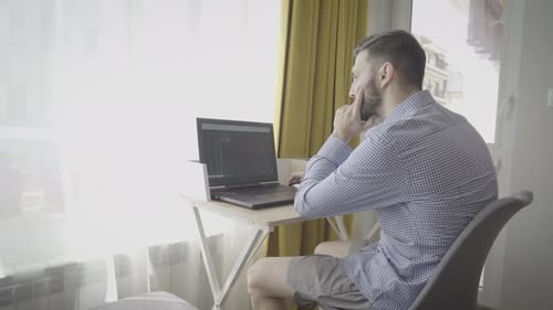 Young Man Works on Laptop in Apartment