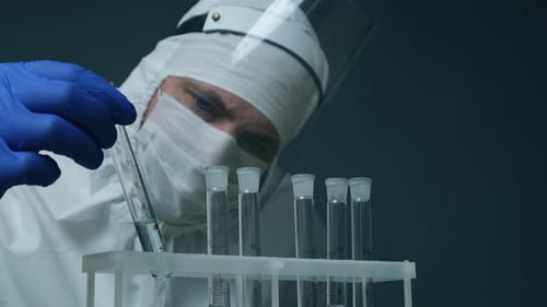 Individual Examining Vial of Clear Liquid in Lab