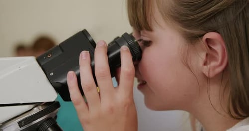 Young Girl Using Microscope for Science in School