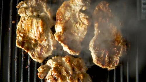 Grilling slice pork steaks. juicy meat steaks cooking on the grill. Slow motion cooking of food