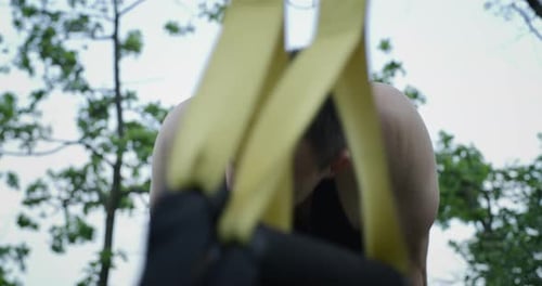 Muscular Man Working Out with Resistance Bands in Nature
