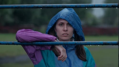 Woman in Hooded Jacket Leaning on Gate in Rain