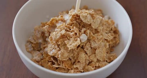 Milk Poured Over Flakes Cereal in Bowl