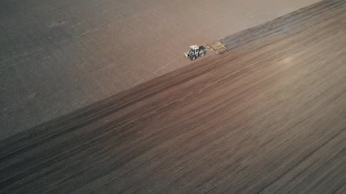 Drone Flies Past the Tractor that Plows the Field