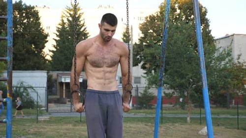 Muscular Man Exercising on Gymnastic Rings Outdoors