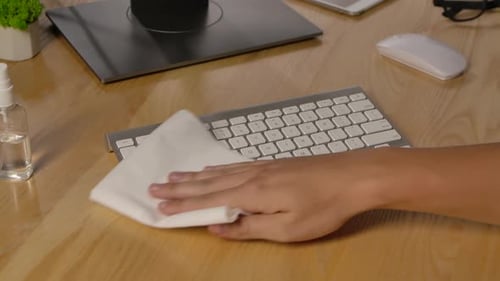 A Man Sprays Antiseptic on a Napkin and Disinfects a White Computer Keyboard and Then Types on It