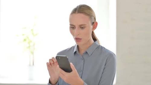 Blond Woman Reacts with Shock to Smartphone News