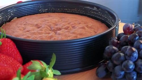 Ein Kuchenboden in einer Form und verschiedene Obstsorten auf einer Küchentheke - Nahaufnahme