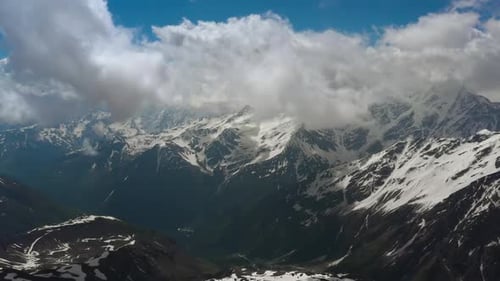 Air Flight Through Mountain Clouds Over Beautiful Snowcapped Peaks of Mountains and Glaciers