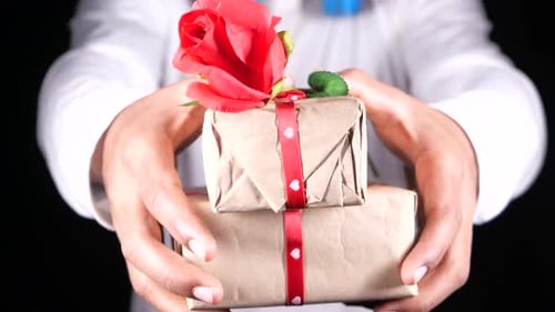 Man Presenting Two Wrapped Gifts with Rose