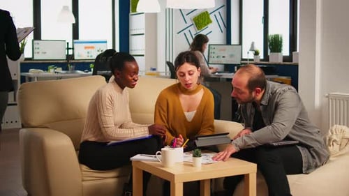 Enthusiastic Team Collaborating on Couch in Modern Office