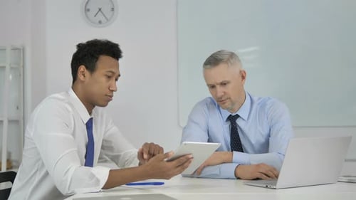 Two Colleagues Discussing Business with a Tablet and Laptop