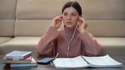 Woman Studying with Notebook and Earphones