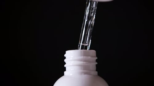 Liquid Drops From Glass Dropper Into Bottle