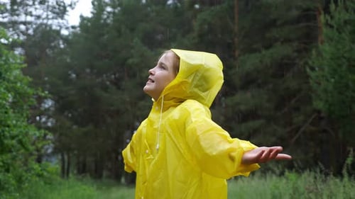 Happy Girl in Yellow Raincoat Enjoys the Rain