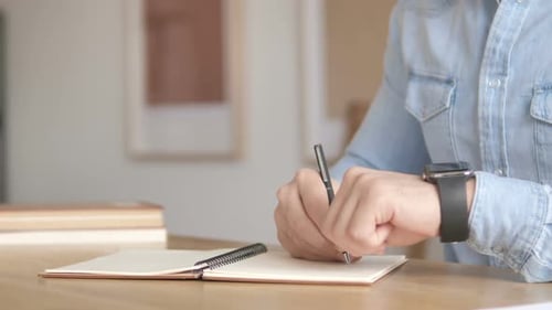 Person writing notes glancing at smartwatch