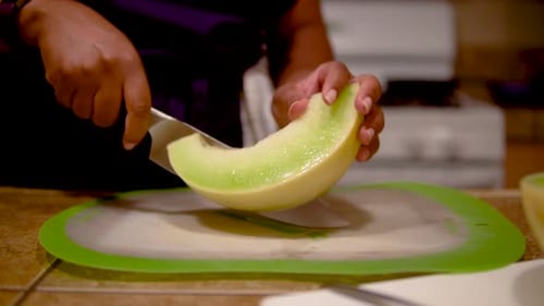 Femme coupant du melon vert miellat en tranches, Gros plan