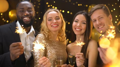 Carefree Friends Enjoying New Year Celebration in Night Club Holding Sparklers