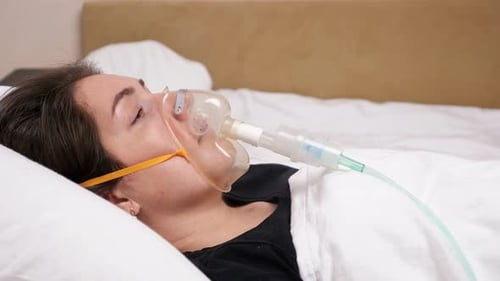 Jeune femme avec un masque facial allongée sur un lit blanc