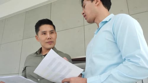 Two Young Men Discuss Business in an Office