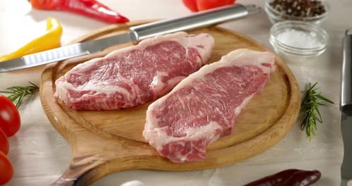 Close Up Raw Steaks and Vegetables on Wood