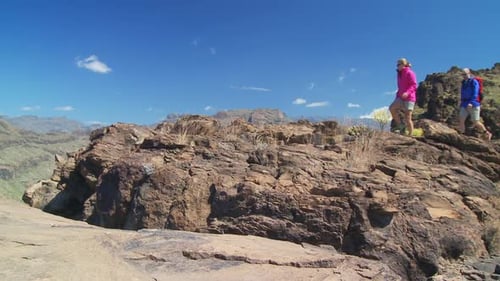 Couple Hiking on Rocky Mountain Top Under Blue Sky