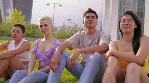 Grupo de jóvenes amigos multiétnicos sentados al aire libre juntos con una sonrisa