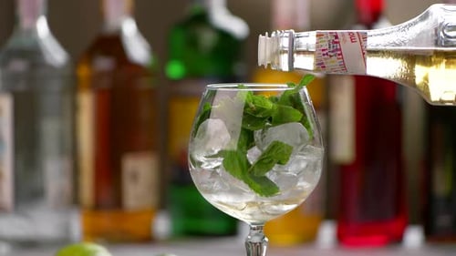 Adding Clear Liquid to Glass of Mint and Ice
