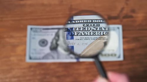 Examining a One Hundred Dollar Bill with Magnifying Glass