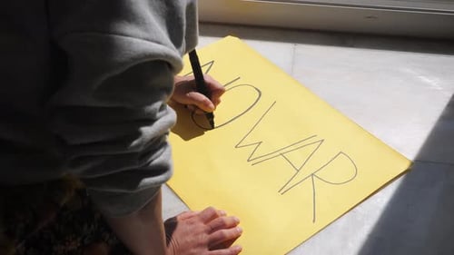 Adult Writes 'NO WAR' on Yellow Paper
