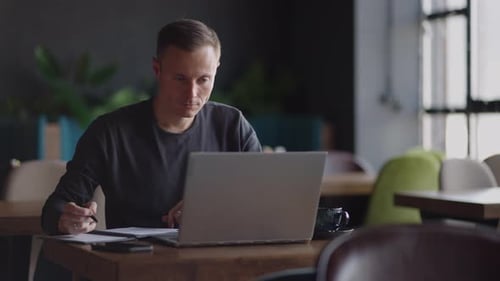 Smiling Man with Works From Home in His Kitchen Using a Laptop