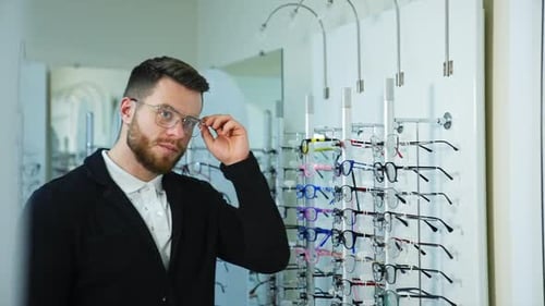 Young man in optics store. Man in optical center trying new eyeglasses