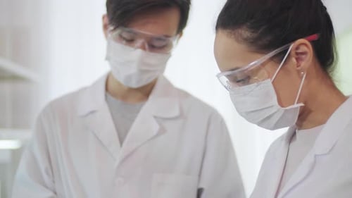 Scientists Reviewing Data in Lab Wearing Protective Gear