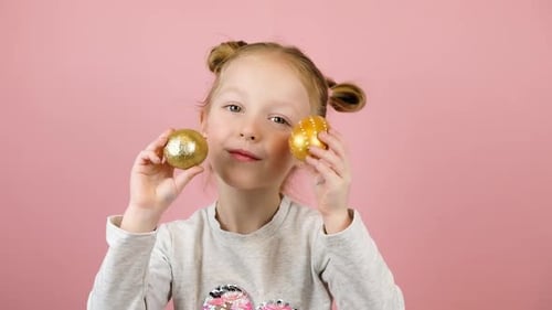 Happy Girl Holding Golden Easter Eggs and Smiling