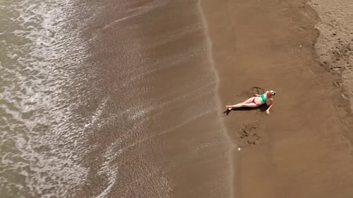 Mädchen ruht am Strand, Ansicht von oben. Vulkanischer Sandstrand.